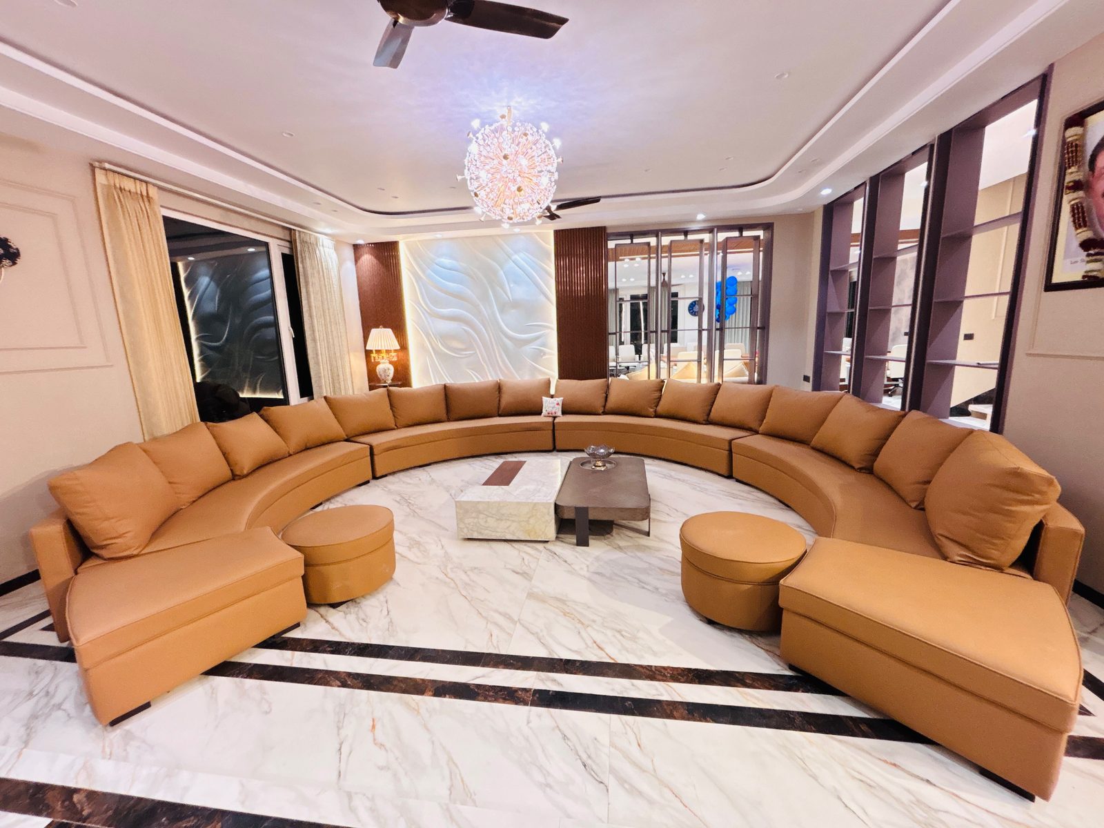 Villa lounge with curved tan leather sofa and chandelier